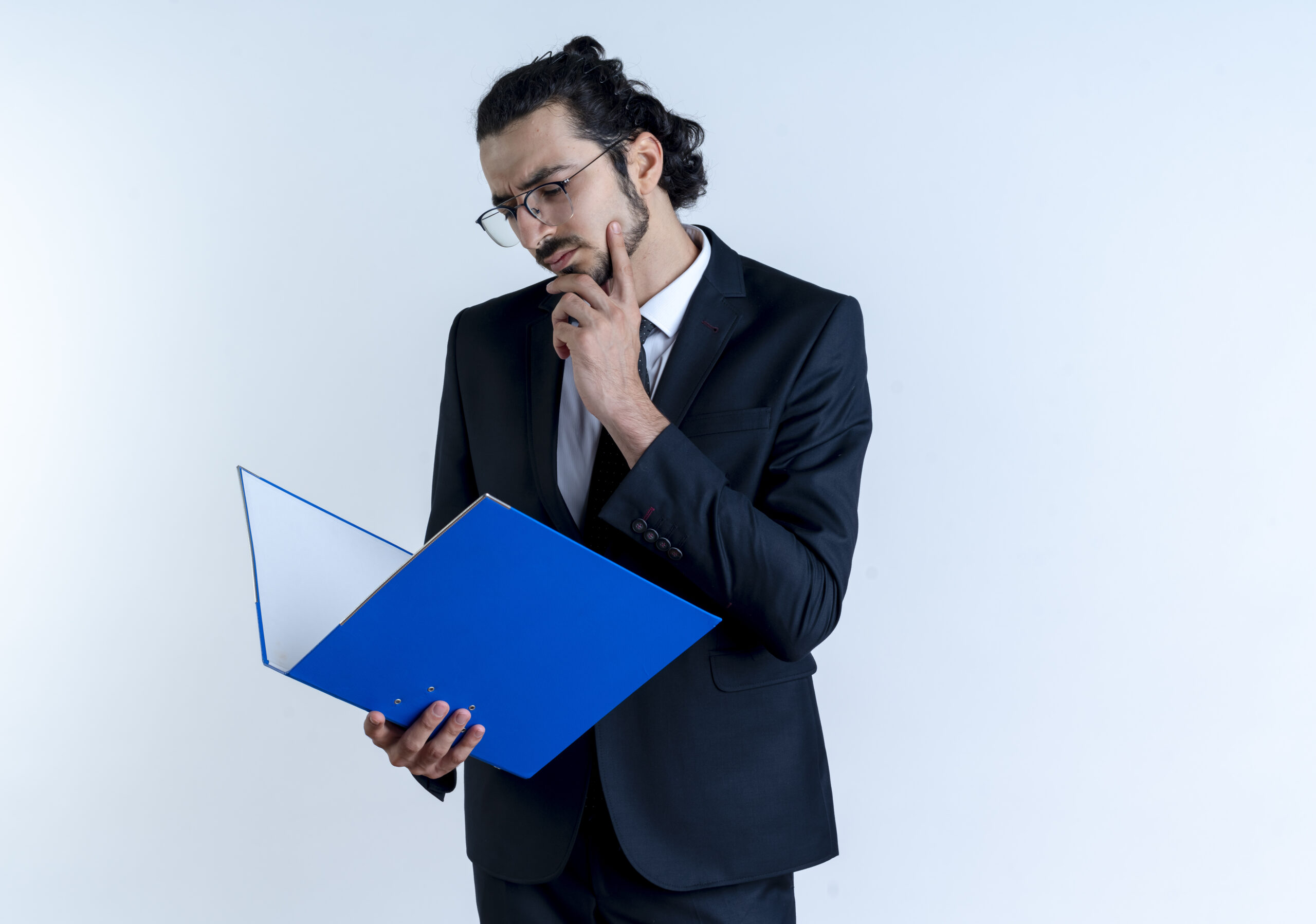 business man in black suit and glasses holding folderlooking at it puzzled standing over white background
